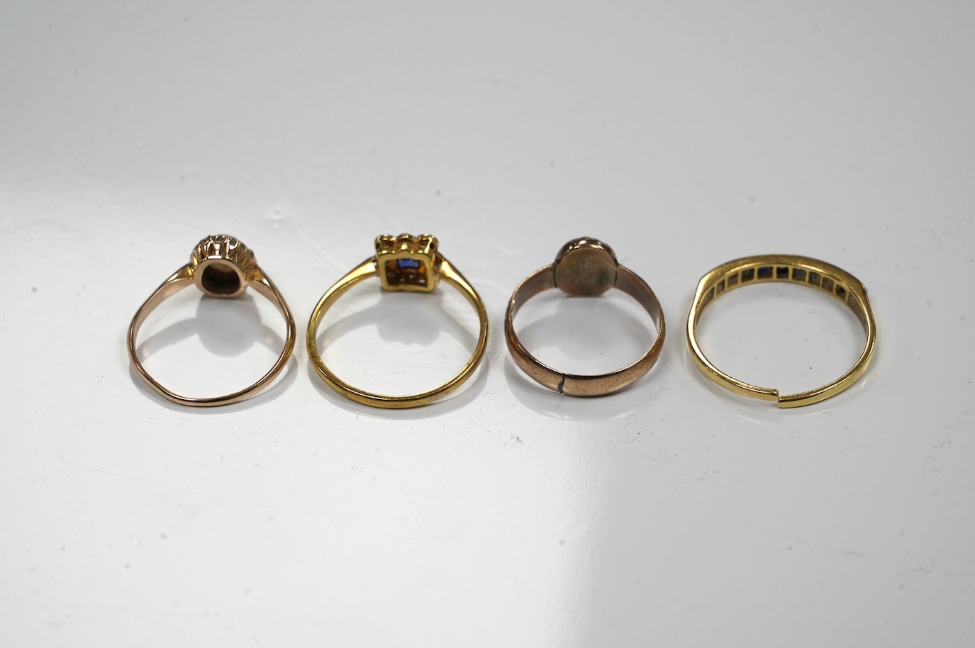 Four assorted gem set rings, including 18ct and plat, sapphire and diamond cluster, 14k, white opal and diamond cluster, an 18ct sapphire and diamond (cut) and an antique garnet set yellow metal ring. Condition - poor to